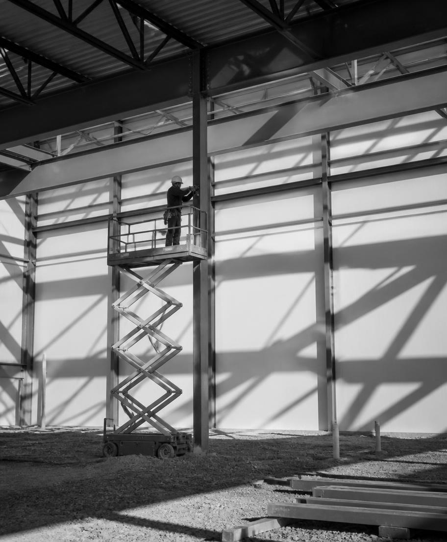 Construction worker on a scissor lift inside a steel building shell